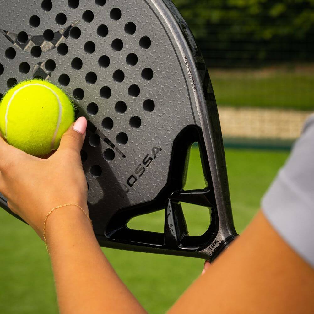 Player holding a padel ball against the black NOSSA Padel CORE racket on an outdoor court