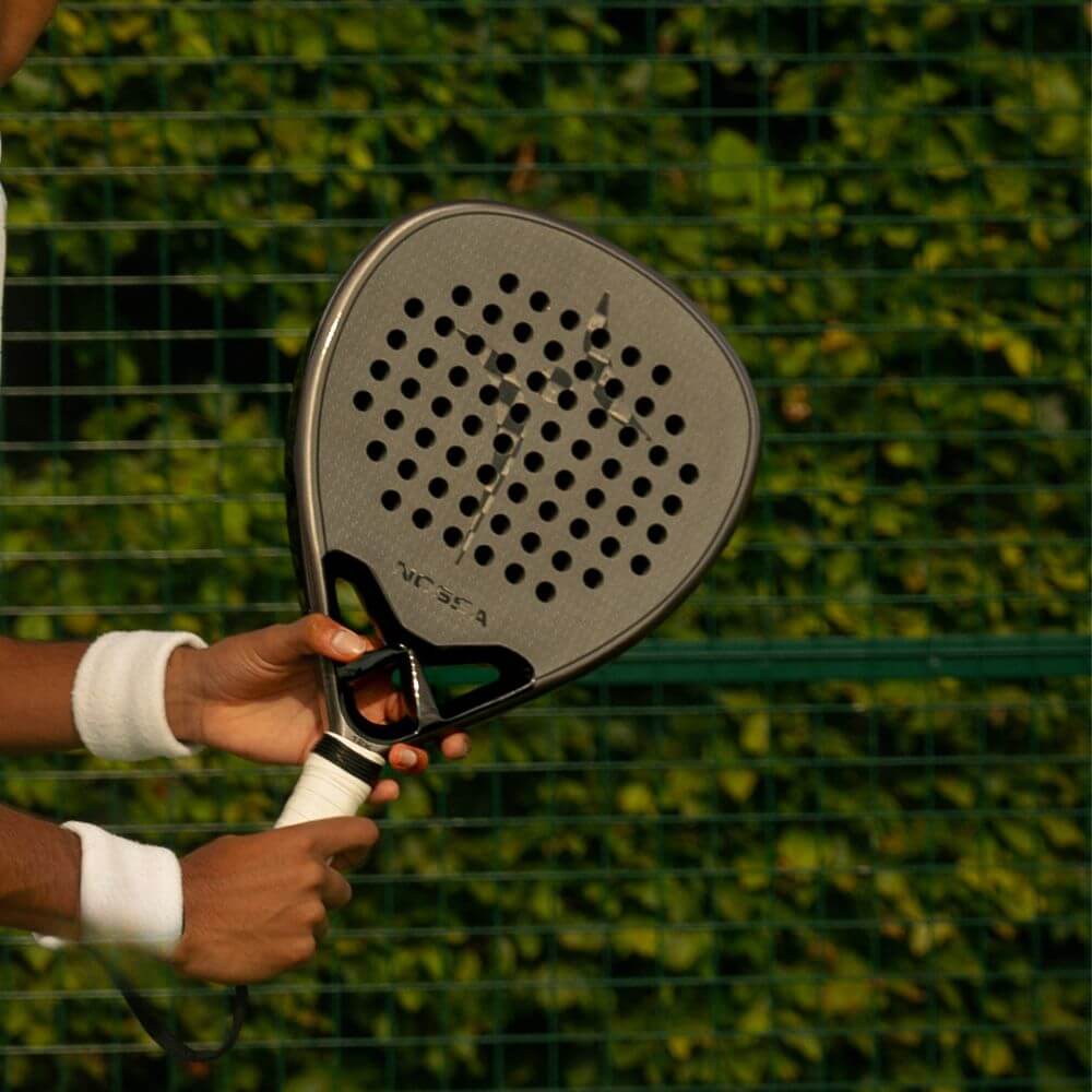 Player holding the black NOSSA Padel CORE racket outdoors